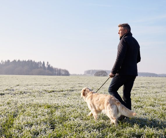 señor pasea por la hierba con perro